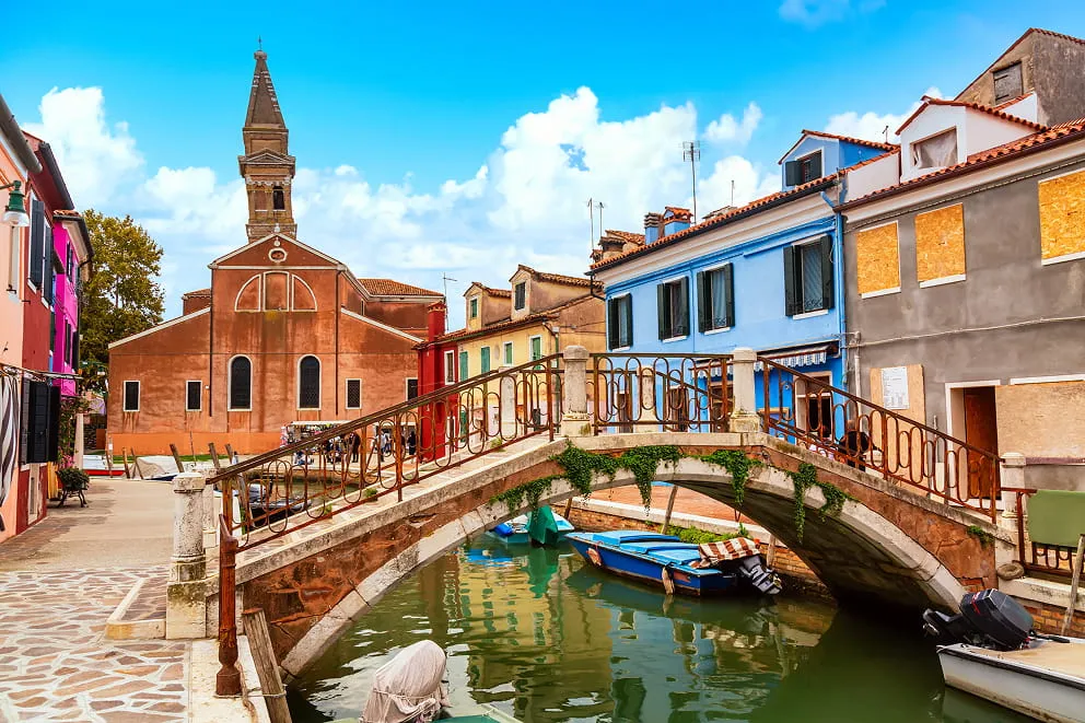 Farbenprächtige Häuser und der schiefe Glockenturm der Kirche San Martino auf Burano